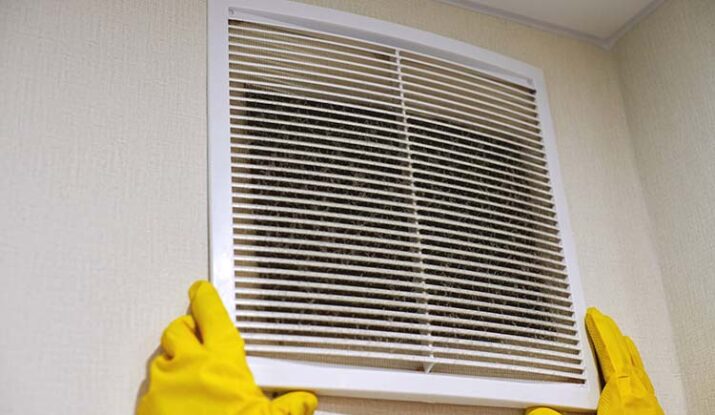 Holding ventilation grill of HVAC for cleaning or replacing.