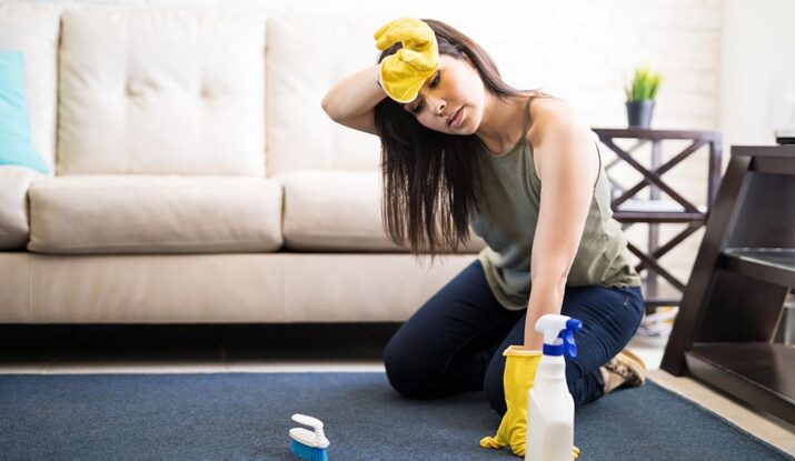 Tired housewife cleaning carpet