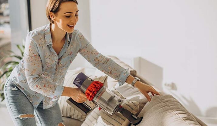 Young woman with rechargeable vacuum cleaner cleaning at home